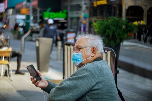 Old man using mobile phone on New York City in wearing face mask as protection against to coronavirus covid-19 flu virus new normal, pandemic.