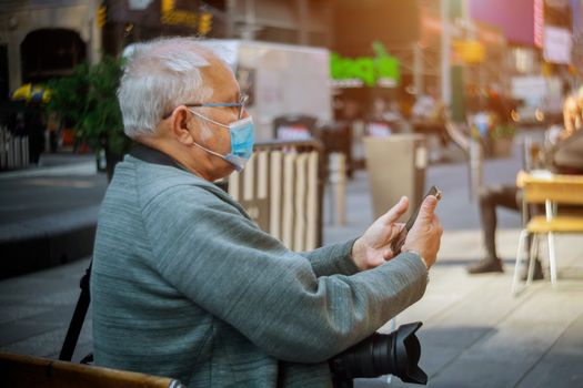 People wearing protective face masks outdoors due to coronavirus epidemic on man with his smartphone in New York USA