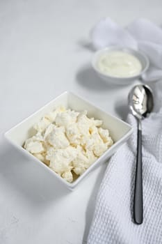 Fresh cottage cheese on the white plate.