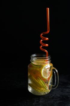 Fresh citrus lemonade in a jug isolated on black background.