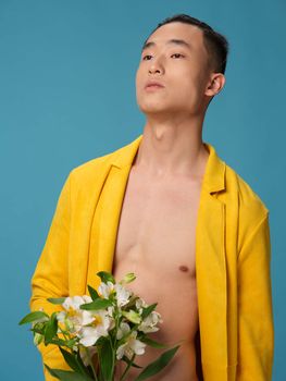 Asian man in yellow coat looking up and white flowers. High quality photo