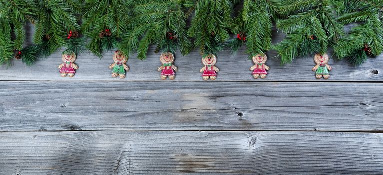 Christmas rustic natural wooden background with evergreen branches and Gingerbread cookie figures  