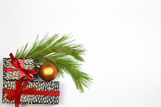 Gifts wrapped with colorful paper and red bows next to Christmas decoration on white background