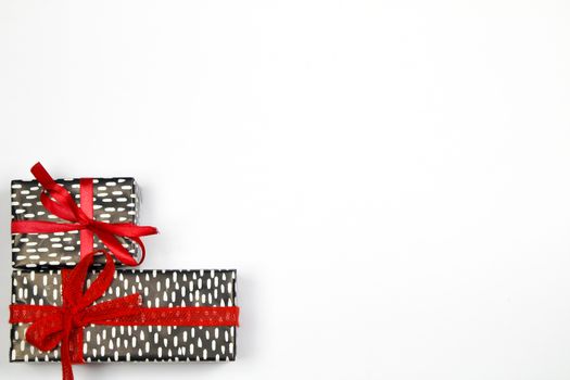 Gifts wrapped with beautiful paper and red bows on white background