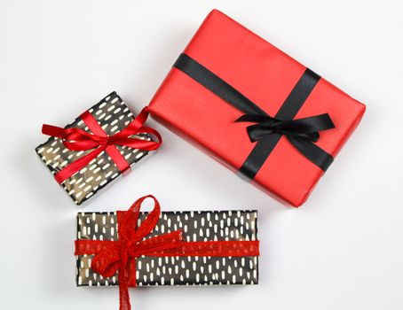 Gifts wrapped with colorful paper and red and black bows on white background