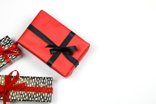 Gifts wrapped with colorful paper and red and black bows on white background