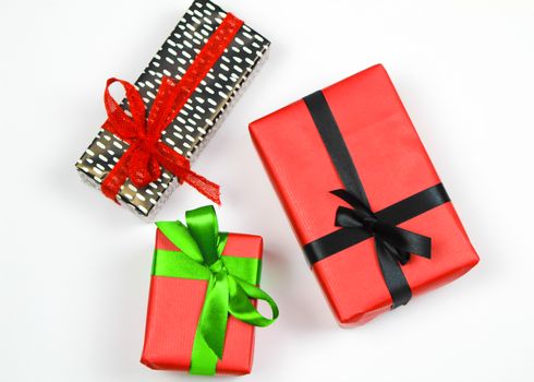 Gifts wrapped with colorful paper and red, green and black bows on white background