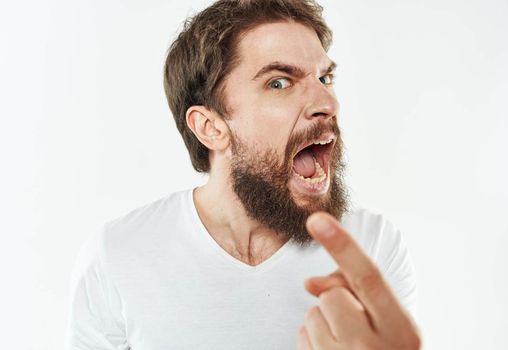 Angry man in a white t-shirt shows a fist gesturing with his hands to the model. High quality photo