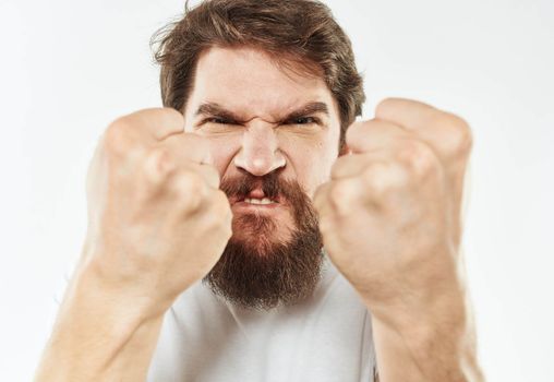 Angry man in a white t-shirt shows a fist gesturing with his hands to the model. High quality photo