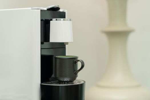 Ceramic cup of coffee on the coffee machine. Coffee capsule machine maker.