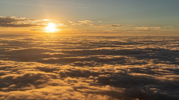 Dramatic sunset scenic. View of sunset above clouds from airplane window.