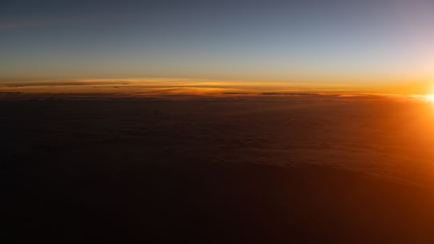 Dramatic sunset scenic. View of sunset above clouds from airplane window.