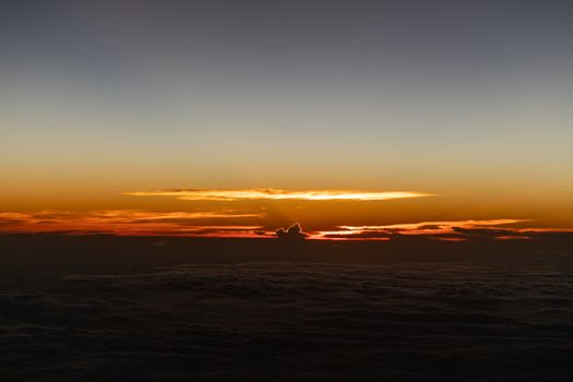 Dramatic sunset scenic. View of sunset above clouds from airplane window.