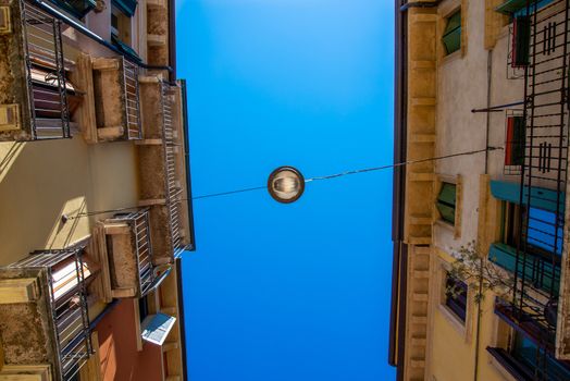 A street lamp in an alleyway in Verona, Italy, suspended across the street from façade to façade using a steel cable.