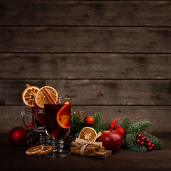 Mulled wine with cinnamon sticks orange fir tree branch and baubles Christmas composition over dark wooden background