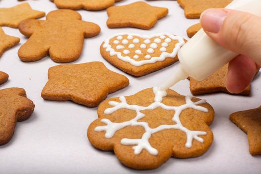 Close up of decorating the gingerbread cookies with white glaze, Merry Christmas concept