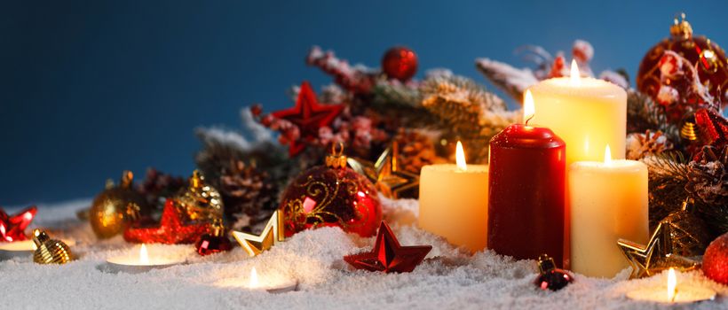 Christmas composition of colorful ornaments balls stars candles and fir tree branches on snow