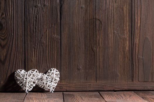 Two wicker hearts on wooden background with copy space for text