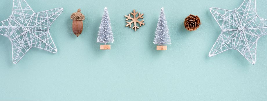 Top view of Christmas holiday decoration ornament composition with Christmas tree, gift star, gingerbread man flat lay with copy space isolated on green background.