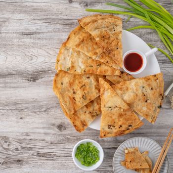 Taiwanese food - delicious flaky scallion pie pancakes on bright wooden table background, traditional snack in Taiwan, top view.