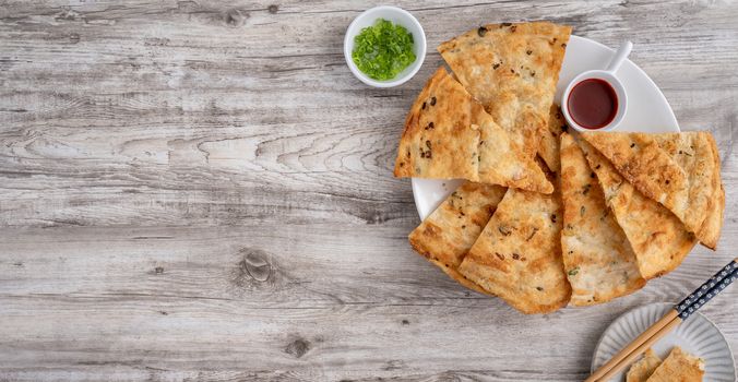 Taiwanese food - delicious flaky scallion pie pancakes on bright wooden table background, traditional snack in Taiwan, top view.