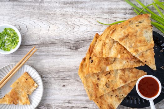 Taiwanese food - delicious flaky scallion pie pancakes on bright wooden table background, traditional snack in Taiwan, top view.