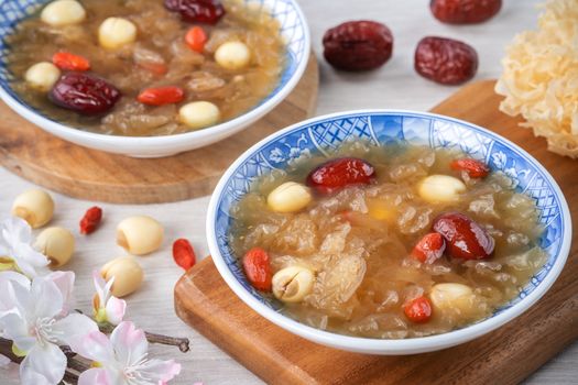 Close up of traditional Chinese sweet snow white fungus soup with lotus seed, red dates (jujube) and wolfberry (goji berry, gojiberry) on white background.