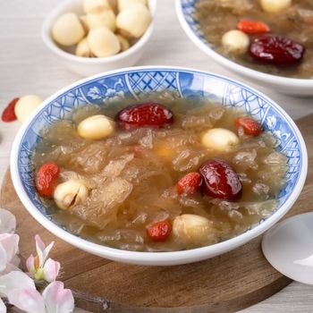 Close up of traditional Chinese sweet snow white fungus soup with lotus seed, red dates (jujube) and wolfberry (goji berry, gojiberry) on white background.