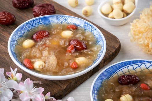 Close up of traditional Chinese sweet snow white fungus soup with lotus seed, red dates (jujube) and wolfberry (goji berry, gojiberry) on white background.