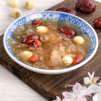 Close up of traditional Chinese sweet snow white fungus soup with lotus seed, red dates (jujube) and wolfberry (goji berry, gojiberry) on white background.