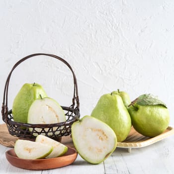 Delicious beautiful guava set with fresh leaves isolated on bright white wooden table background, close up.