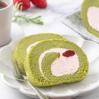 Delicious Matcha Swiss Roll Cake slices with strawberry icing cream on white background, close up.