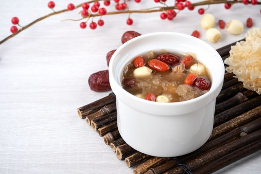 Close up of traditional Chinese sweet snow white fungus soup with lotus seed, red dates (jujube) and wolfberry (goji berry, gojiberry) on white background.