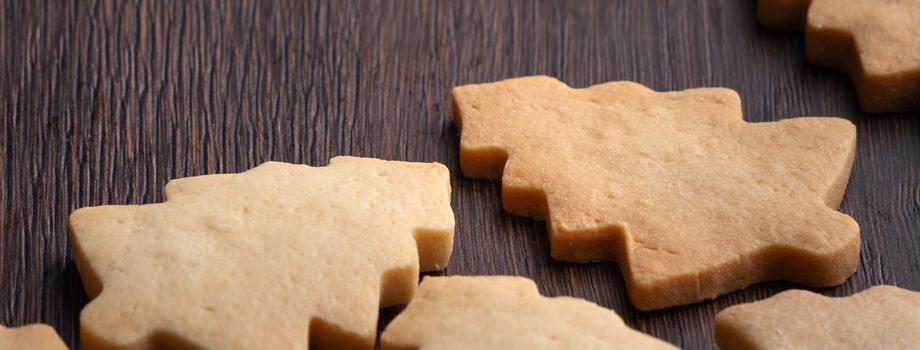 Close up of plain flavor gingerbread Christmas tree cookie on wooden table background. Food for Christmas holiday celebration.