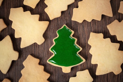 Top view of decorated green plain flavor gingerbread Christmas tree cookie on wooden table background with copy space, concept of holiday celebration.