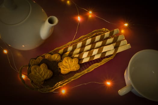 Tubes with cream in a basket, a teapot and a cup, top view