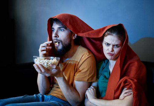 scared woman with a red plaid on her head and a man with a plate of popcorn. High quality photo