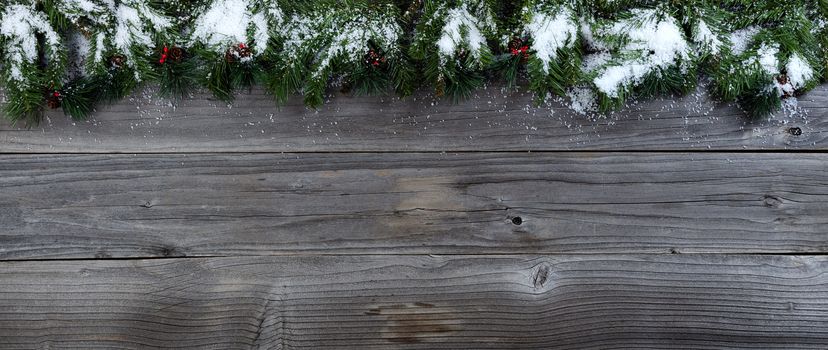 Merry Christmas concept on rustic natural wooden background with snow covered Fir branches with plenty of copy space   