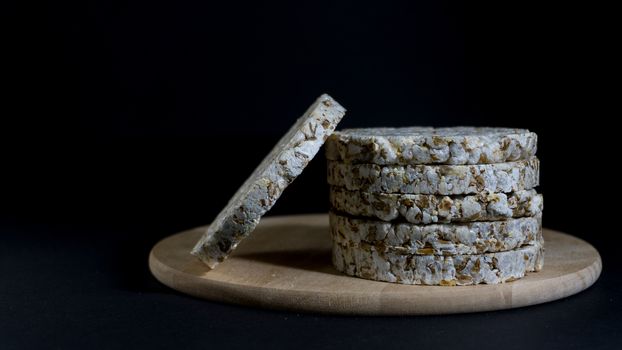 Grain crispbreads crispy rice and diet bread. Stack of puffed whole grain crispbread. Rice cake puffed rice on black background.