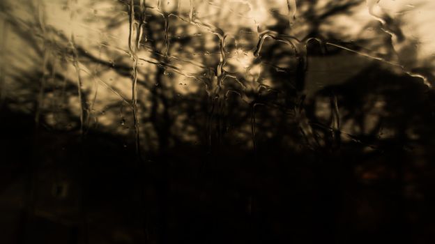 Water on the window. Rain on the window glass. Shadow on tree and nature through glass and rain. Shadow of house building