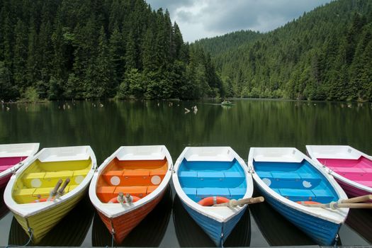 Colorful boats staying on the lake and moutains and forest behind Bicaz Lake