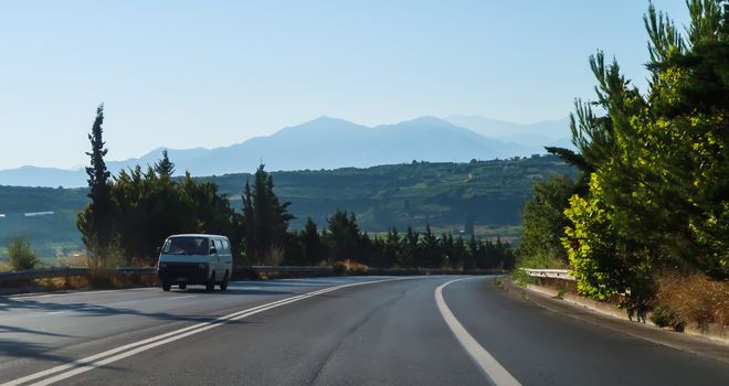 Car on the road and mountains behind it in Crete, Greece