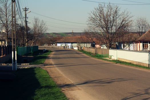 Road and shadows during day in a village in Romania