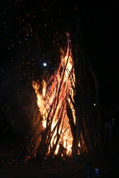 Wood burning at night. Campfire at touristic camp in mountains. Flame and fire spark on dark abstract background. Hellish fire element. Orange fire at night