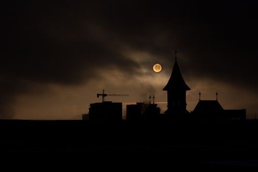 Fade sunrise with fog and dark sky with silhouette church and buildings construction