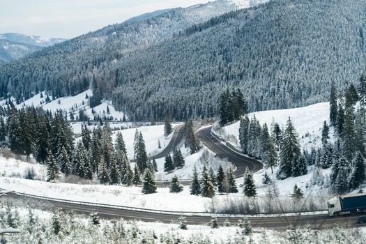 Road bending in the mountains with truck on the road - landscape of mountains after heavy snow in winter in Romania