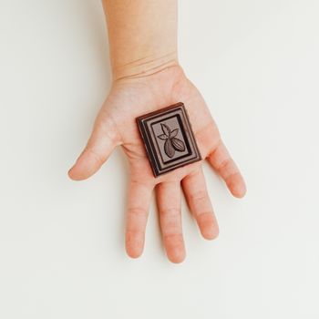 child holding a piece of dark chocolate bar in hand