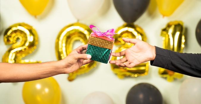 Close up of hands giving present gift box in 2021 new year celebration on decorated background - Concept of gift sharing on new year holydays