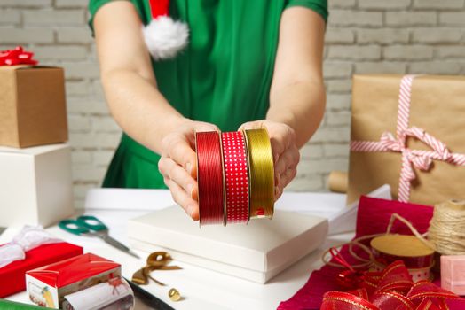 women select ribbons for wrapping gifts. diy Gift wrapping for Christmas and New Year. Handmade. packing and wrapping service concept