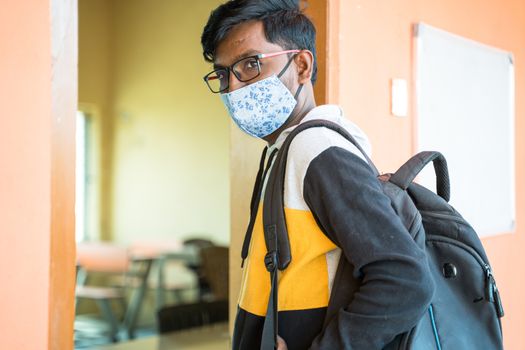 College student with face mask looking into camera before entering classroom - concept of college reopen, new normal lifestyle after coronavirus or covid-19 pandemic.